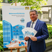Das Bild zeigt Bayerns Bauminister Christian Bernreiter mit den fünf Flyern zur Wohnraumförderung..
